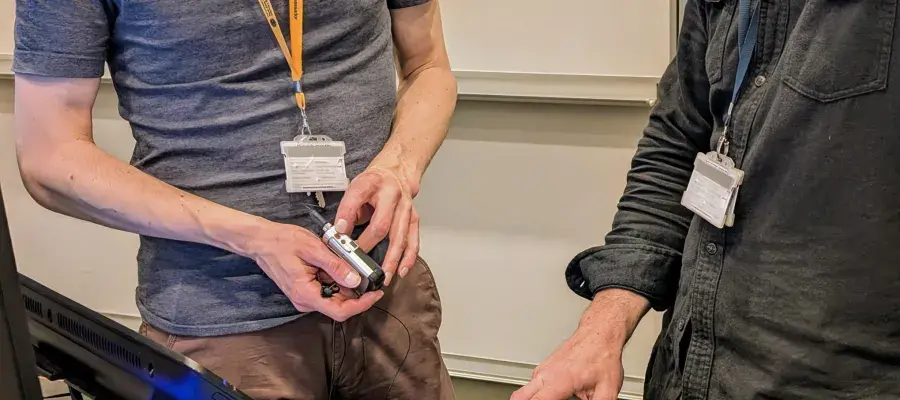 A student with a yellow lanyard explaining how to use a mic to a lecturer