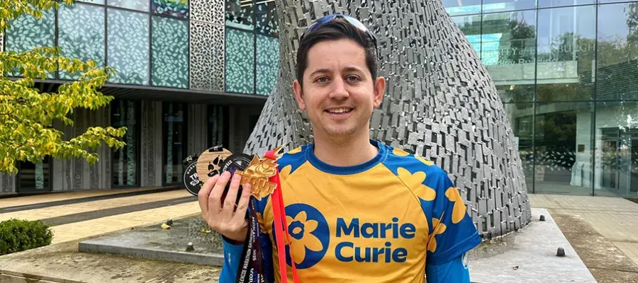 image of man in marie curie running top holding four medals 