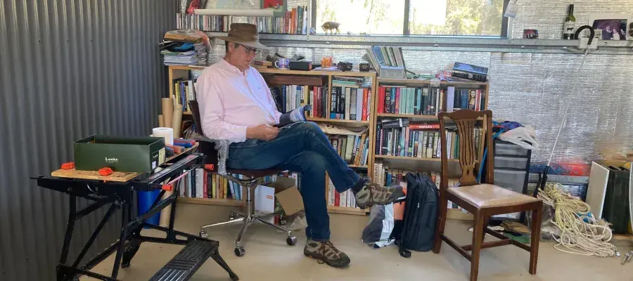 Prof Jonathan Rushton sitting on a chair in his home, reading a book