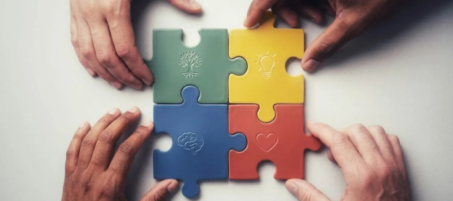 four hands each placing a seperate jigsaw piece together