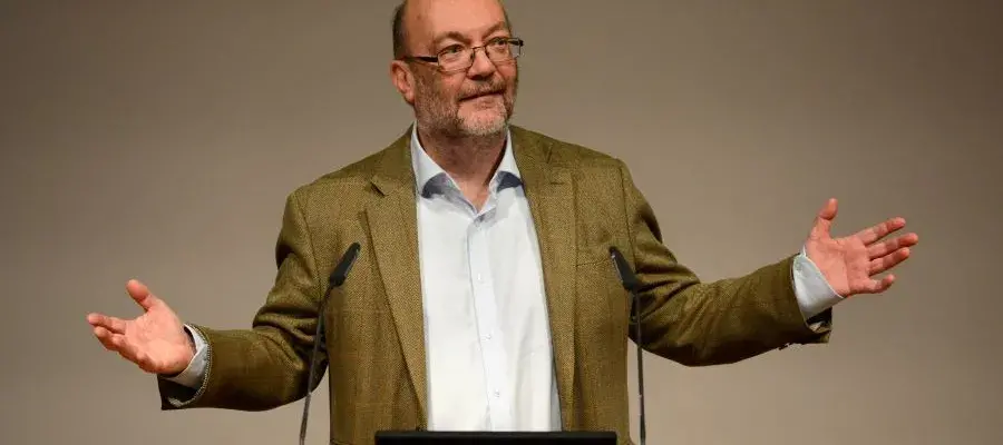 Professor Bruce Whitelaw stands at a podium with his arms outstretched.