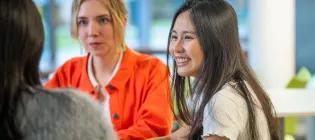 Three students having a conversation while sitting at a table
