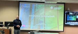 Ivan Pocrnic standing at the front of the room beside a screen introducing the workshop