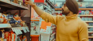 A man chooses items from a supermarket shelf.