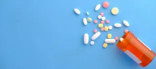 image of a container on its side with a variety of tablets spills from it