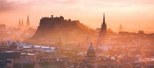 Edinburgh castle rising proud in front of a misty sunset