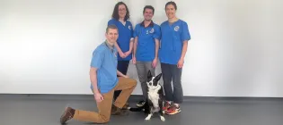 group of two male and two female vets in blue scrub tops smiling at the camera