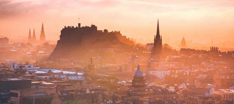 Edinburgh castle rising proud in front of a misty sunset