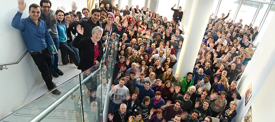 A large group of people waving at the camera