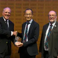 Head of the Roslin Foundation, John Brown, shakes Prof Yamanaka's hand, while Prof Whitelaw stands next to them.