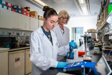 Two female scientists work together at a lab bench.