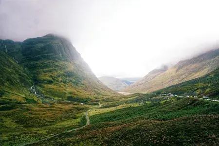 A view of Scottish mountain landscape featuring a river and road, with low cloud.