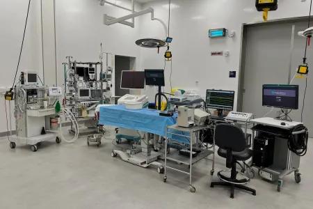 trolleys, screens, computer equipment around a table prepared for a patient in a large clinical room