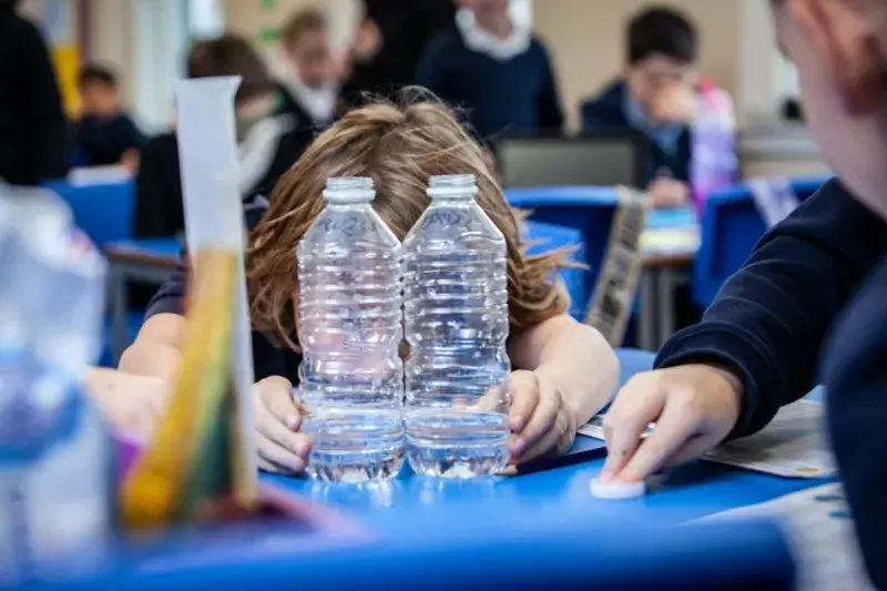A schoolchild checks water in two bottles is equal