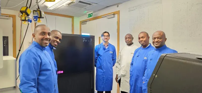 Scientists in lab coats are pictured standing by equipment in the Edinburgh Genomics facility.