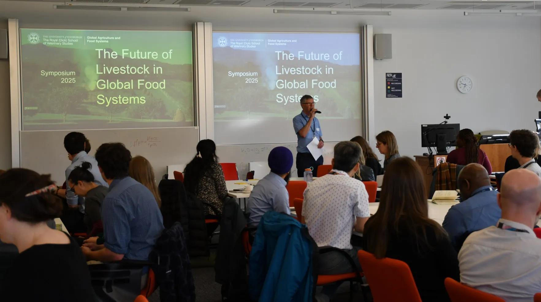 Professor Alan Duncan stands in front of a room of seated delegates, in front of a screen that reads The Future of Livestock in Global Food Systems