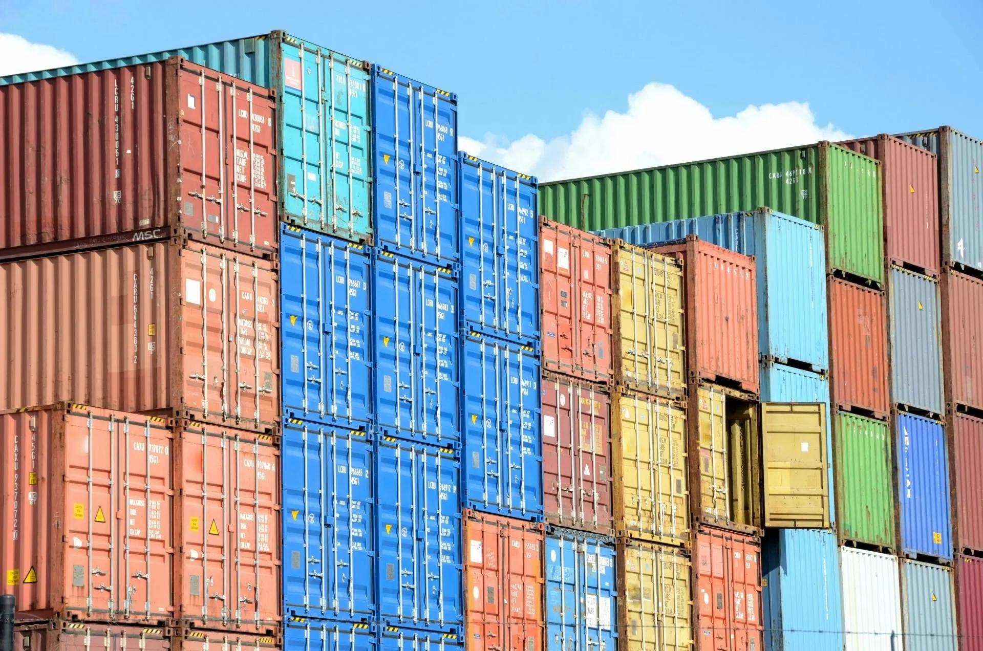 Coloured shipping containers are stacked up in a port.