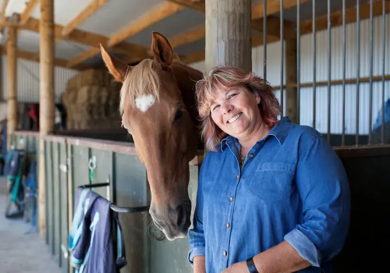 Natalie Waran stands beside a stabled horse.
