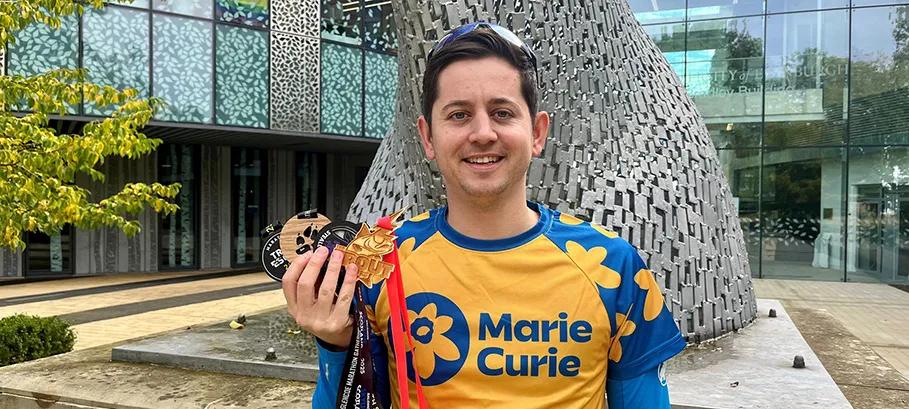 image of man in marie curie running top holding four medals 