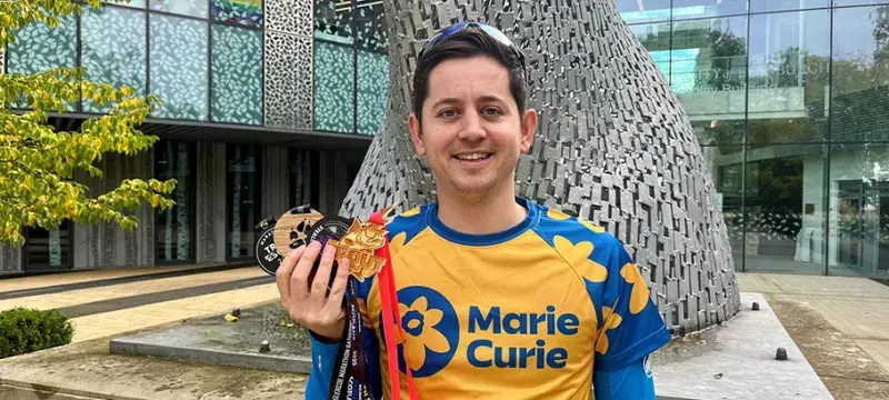 image of man in marie curie running top holding four medals 