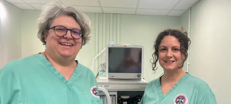 image of two females in green scrub tops standing next to an anaethesia machine and smailing to the camera