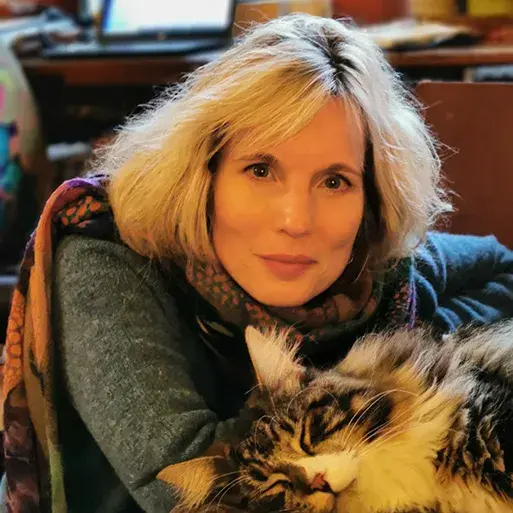 image of woman with blkond mid-length hair and brown tabby cat looking into the camera