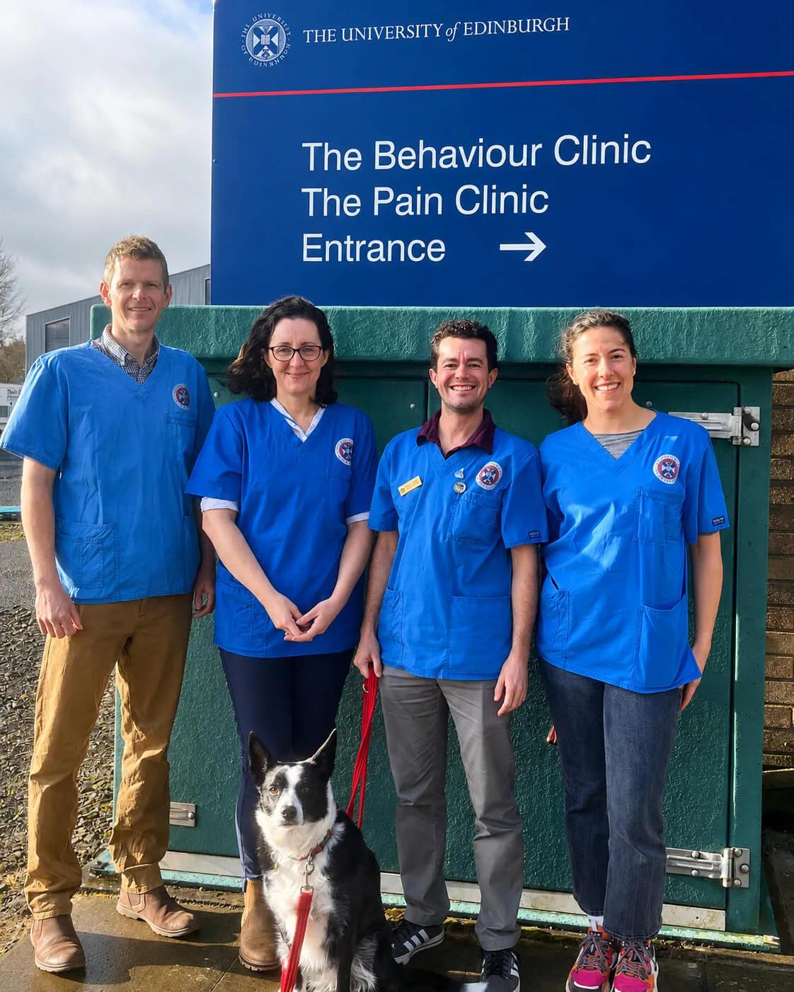 group of two male and two female vets in blue scrub tops smiling at the camera