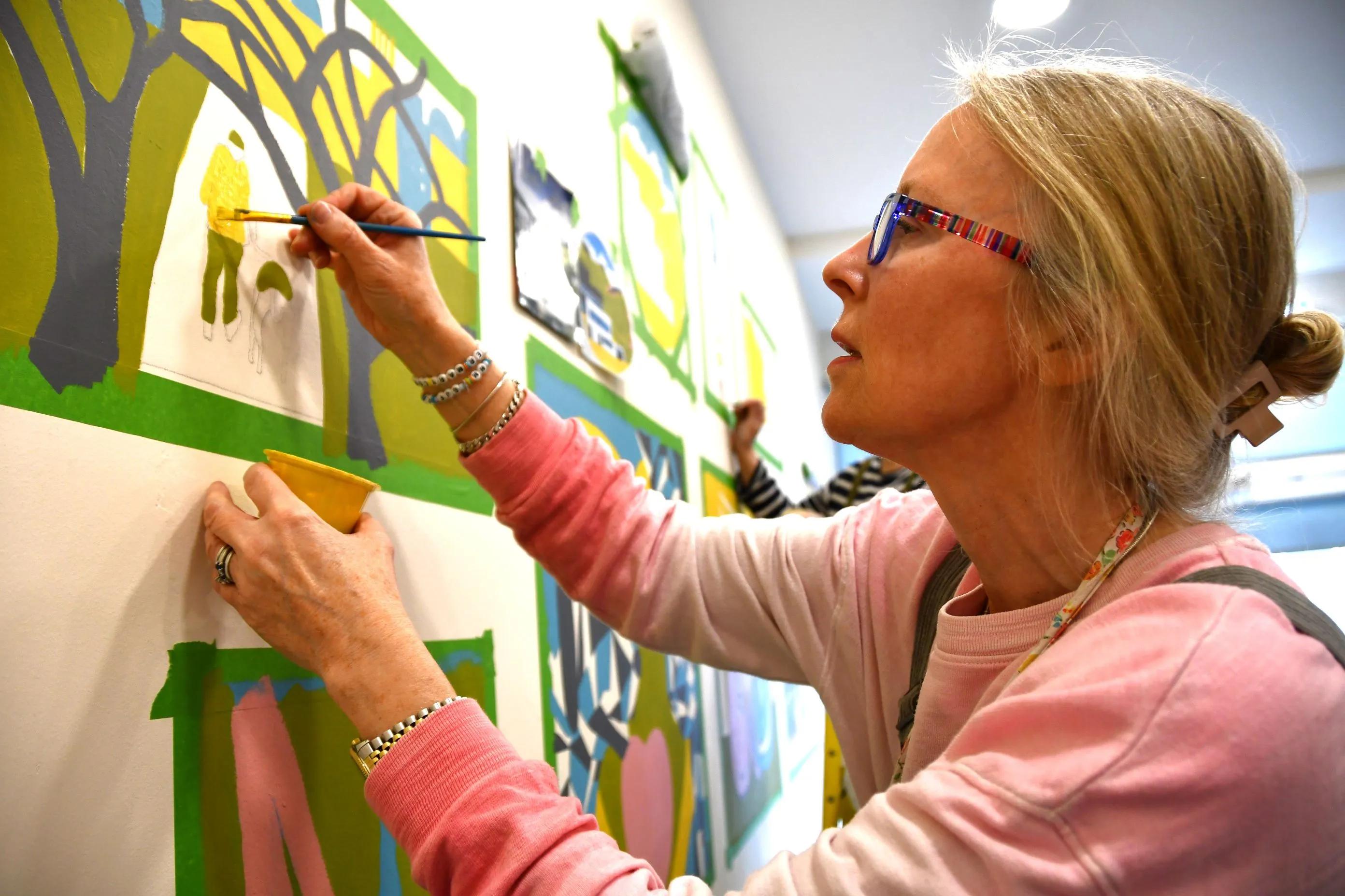 A close-up shot of an art student painting a colourful mural