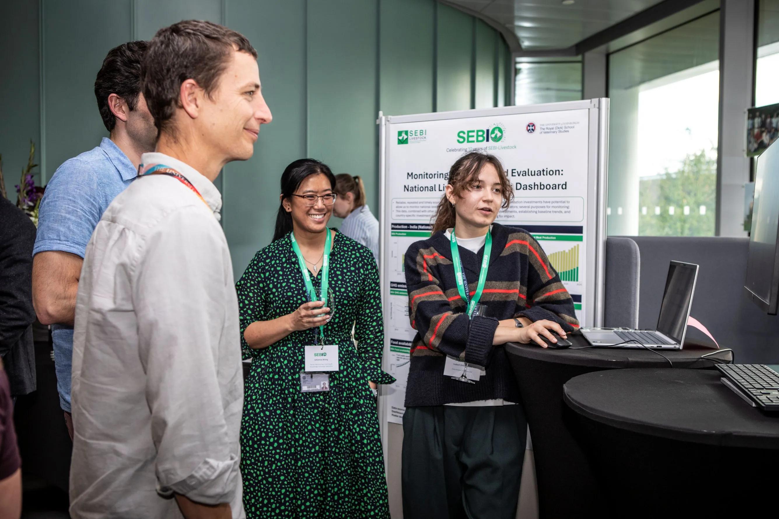 Four people look with interest at a poster display
