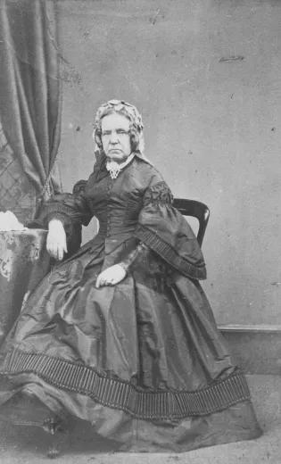Mary Dick, seated and unsmiling, looks directly at the camera.