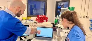 image of two vets looking at a brain activity trace on a laptop with a canine patient in the background