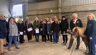 A group of people in a barn with a toy pony