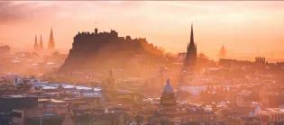 Edinburgh castle rising proud in front of a misty sunset