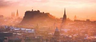 Edinburgh castle rising proud in front of a misty sunset
