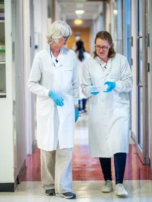 Scientists in discussion as they walk in a lab corridor.