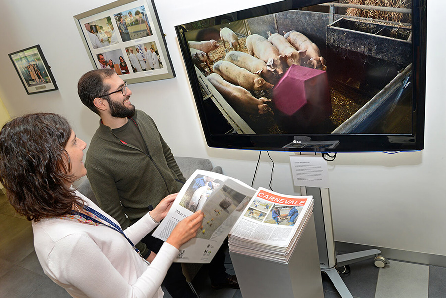 Two people watching the \"Carnevale\" video on a TV.