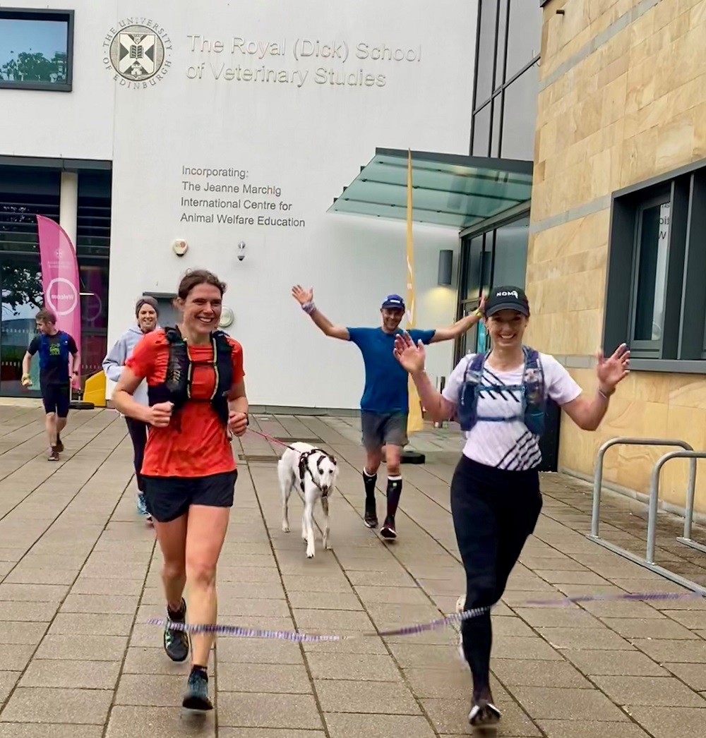 Alice Sheldon and Jasmin Paris crossing the marathon finish line in front of the Dick vet teaching building