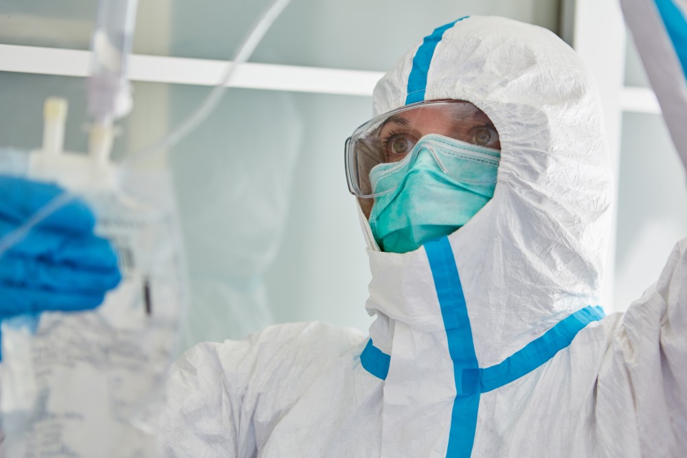 Doctor in protective clothing in hospital intensive care unit treats Covid-19 patient with infusion during the coronavirus pande