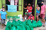 A group of people gathered around a pile of plastic bags containing things