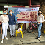 A group of people in front of a sign that says \"MARKET ni MISIS\"