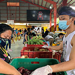 A group of people gathered around a pile of plastic bags containing things